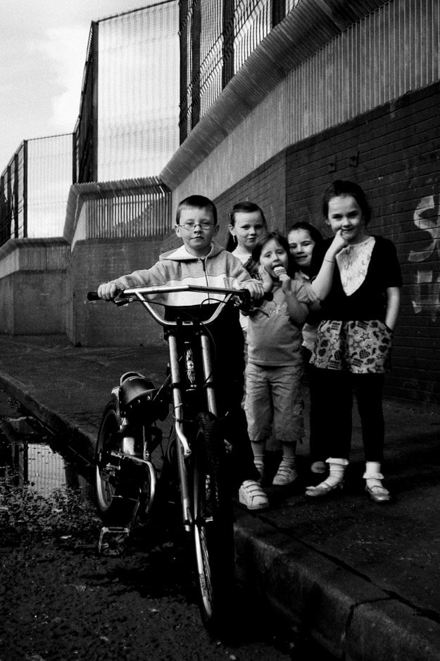 Children posing in front of peace wall in the nationalist Short Strand/Belfast.