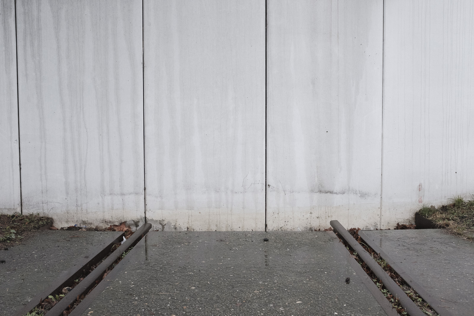 A section of railway track leads towards a tall concrete wall at the former Moabit freight station in Berlin, a deportation station from which over 32,000 people were deported between 1941 and 1945.
